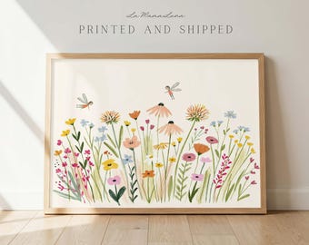 May include: A framed horizontal art print featuring a field of colorful wildflowers in shades of yellow, pink, orange, and blue, with two small flying fairy figures. The text La Mama Luna PRINTED AND SHIPPED is centered above the floral illustration.