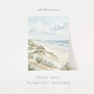 May include: A watercolor art print featuring a coastal landscape with sand dunes, beach grass, and a blue ocean under a cloudy sky. The text La MamaLuna appears at the top, and the text PRINT ONLY FRAME NOT INCLUDED appears at the bottom.