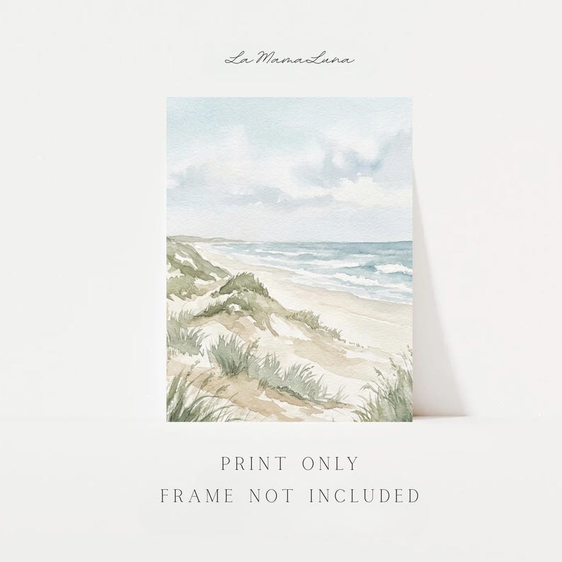 May include: A watercolor art print featuring a coastal landscape with sand dunes, beach grass, and a blue ocean under a cloudy sky. The text La MamaLuna appears at the top, and the text PRINT ONLY FRAME NOT INCLUDED appears at the bottom.