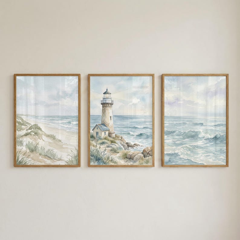 May include: A set of three rectangular wall art prints in light wood frames. The left print shows a sandy beach with dunes, the center print features a lighthouse on a rocky coast, and the right print depicts ocean waves under a cloudy sky.