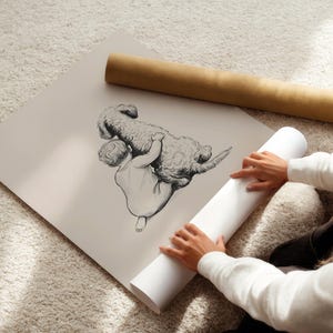 May include: A black and white illustration of a child and a dog. The child is holding the dog. The illustration is on a large, off-white print. A rolled-up print and a brown tube are also in the image.