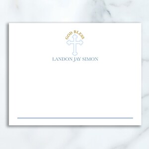Peut inclure: Une carte blanche avec une croix bleue et le texte "God Bless Landon Jay Simon" en lettres dorées. La carte a une ligne bleue en bas.