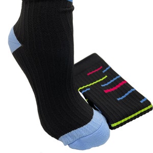 May include: A pair of black socks with colorful stripes. The socks have a light blue heel and toe. One sock is folded and the other is on a foot.