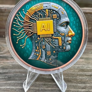 May include: A round, teal-colored coin featuring a profile of a human head with circuit board details. The coin has the text "AI" on a gold-colored chip. The coin is displayed on a clear plastic stand.