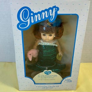 Puede incluir: Mu&ntilde;eca Ginny, "Our Little Mermaid", en una caja. La mu&ntilde;eca mide 20 cm y lleva un vestido de sirena verde y tiene el pelo rojo. La caja tiene el logotipo de Ginny y una ventana transparente.