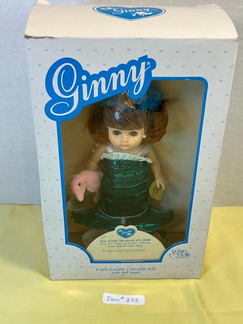 Puede incluir: Mu&ntilde;eca Ginny, "Our Little Mermaid", en una caja. La mu&ntilde;eca mide 20 cm y lleva un vestido de sirena verde y tiene el pelo rojo. La caja tiene el logotipo de Ginny y una ventana transparente.