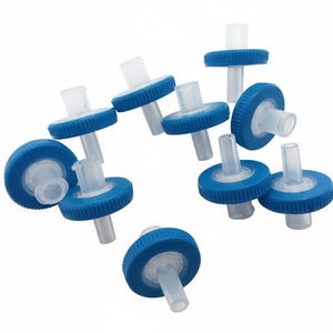 Puede incluir: Una colección de pequeños dispositivos de filtro blancos y azules. Cada filtro tiene un cuerpo cilíndrico con una tapa azul y una salida cilíndrica transparente. Los filtros están dispersos sobre un fondo blanco.