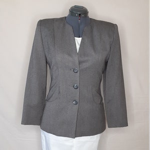 May include: A gray blazer with a V-neck and four buttons. The blazer has a slightly fitted silhouette and is made of a textured fabric.