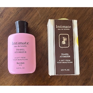 May include: A pink Revlon "Intimate" travel atomizer and its matching box. The bottle and box both feature the text "Intimate eau de toilette" and "Travel Atomizer". The box has a brown and white design with a gold emblem.