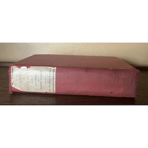 May include: A vintage, burgundy-colored book titled "The Decameron of Boccaccio" with text on the spine. The book is illustrated by Leopold Flameng. The book's cover is slightly worn, suggesting its age.