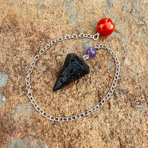 May include: A black obsidian pendulum with a silver chain and red and purple beads.