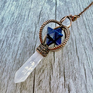 Pode incluir: Um pêndulo cor de cobre com uma ponta de cristal de quartzo transparente e uma pedra em forma de estrela azul escura. O pêndulo apresenta um design de metal decorativo e um anel torcido em forma de corda. A corrente também é cor de cobre.