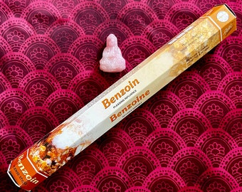 May include: A box of Benzoin incense sticks with a pink Buddha statue on a red patterned surface. The box is labeled "Benzoin Pleasing Influence Benzoine"