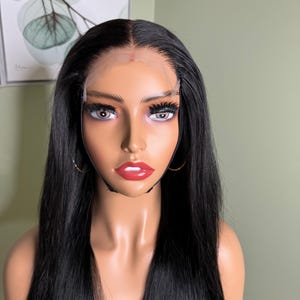 Puede incluir: Una peluca larga y lisa de cabello humano negro con un frente de encaje. La peluca est&aacute; en una cabeza de maniqu&iacute;.