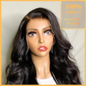 Può includere: Testa di manichino con una parrucca nera e ondulata. La parrucca ha un frontale in pizzo ed è etichettata "200% Density, Glueless - HD Lace". Il manichino ha un trucco completo con rossetto rosso e lunghe ciglia.
