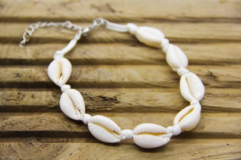 white cowrie shell anklet on a piece of driftwood