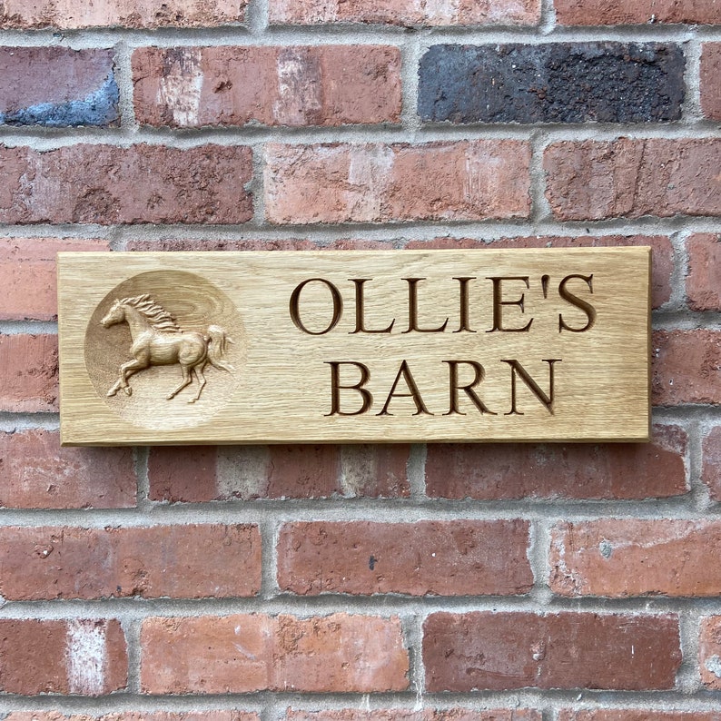 May include: A wooden sign with the text "Ollie's Barn" and a carved image of a horse running to the right.
