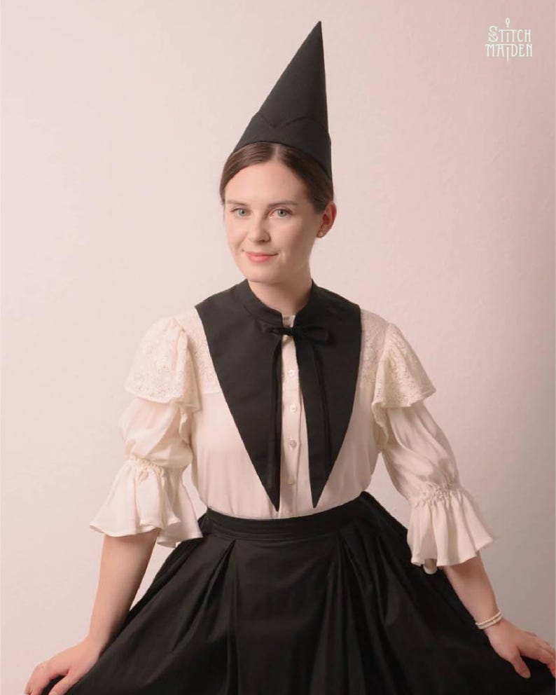 May include: A person wearing a black, pointed hat and a black and white outfit. The outfit includes a black collar with a bow, a white blouse with lace sleeves, and a black skirt. The image has the text "Stitch Maiden" in the upper right corner.