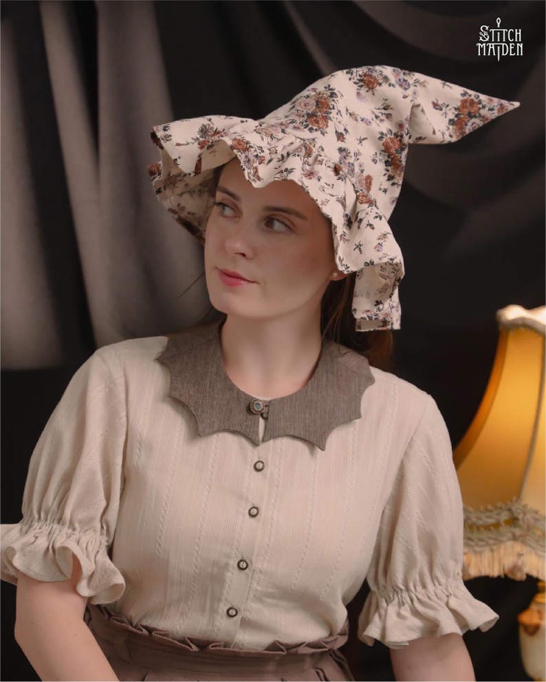 May include: A cream blouse with a brown, scalloped collar and button-down front. The blouse has short, ruffled sleeves. A floral print witch hat with a pointed crown and ruffled brim is worn.