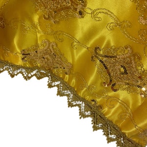 May include: Gold fabric with a gold lace trim and a pattern of sequins and embroidery.