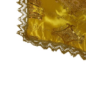 May include: Gold fabric with a decorative pattern and gold sequins. The fabric has a gold lace trim.