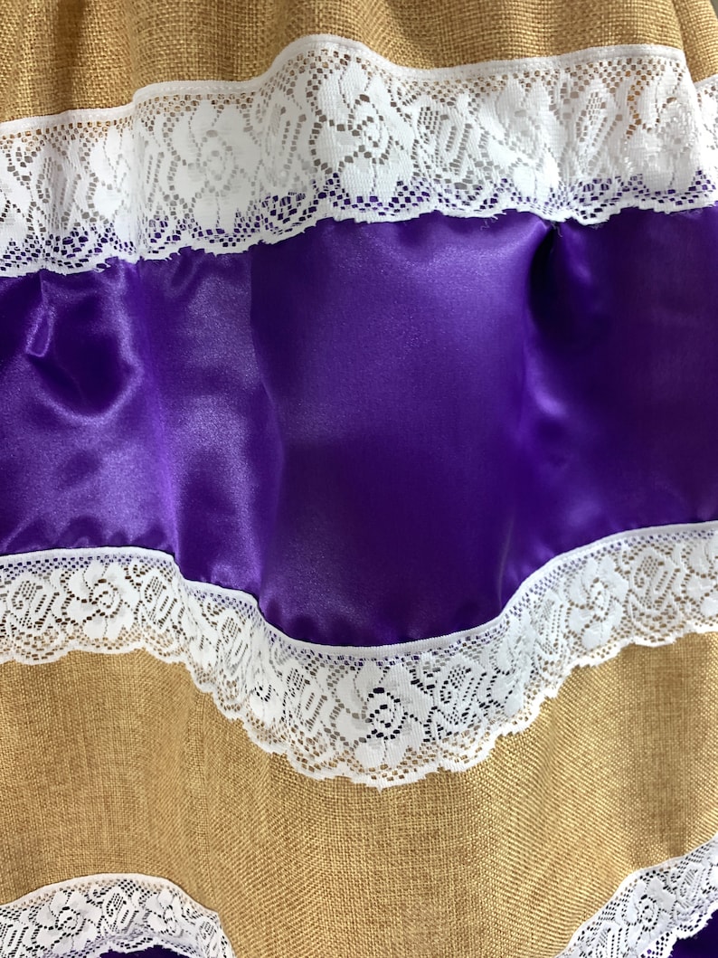 May include: A brown burlap fabric with two layers of white lace trim and a layer of purple satin fabric.
