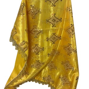 May include: A yellow satin fabric with a gold and black embroidered design. The fabric has a scalloped edge and is perfect for a variety of crafting projects.