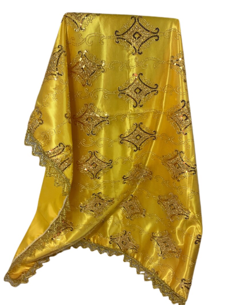 May include: A yellow satin fabric with a gold and black embroidered design. The fabric has a scalloped edge and is perfect for a variety of crafting projects.