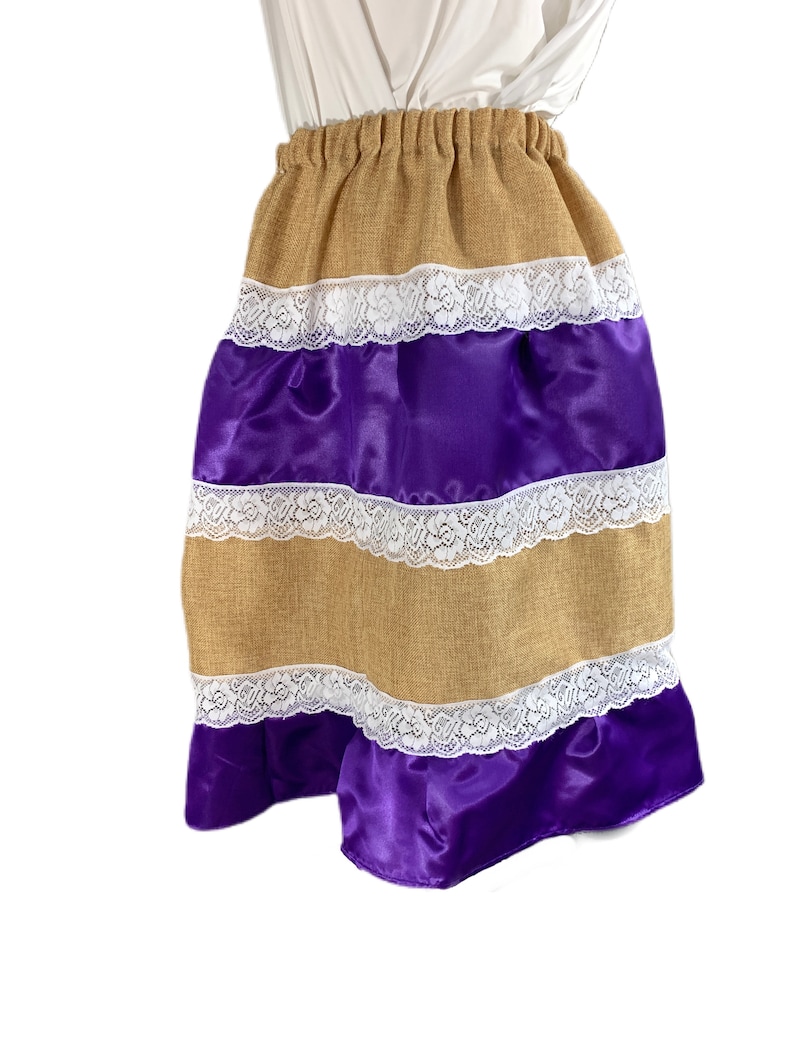 May include: A brown and purple skirt with white lace trim. The skirt is made of burlap and satin.