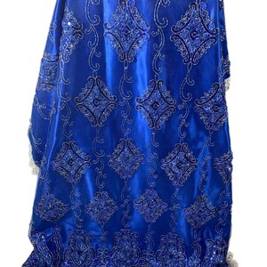 Puede incluir: Tela azul real con un patr&oacute;n bordado en plata y azul. La tela tiene un acabado satinado brillante y un ribete de flecos plateado y azul.