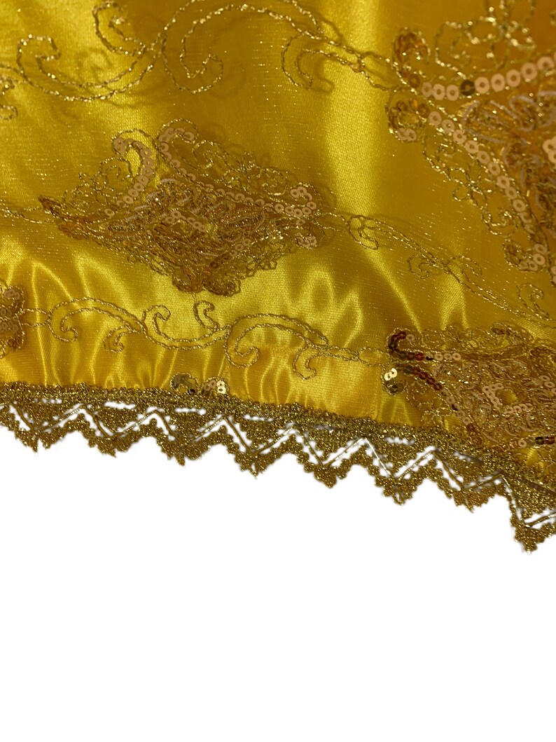 May include: Gold fabric with a gold lace trim and a sequined design. The fabric has a satin finish.