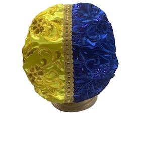 Puede incluir: Un cubrecabezas de tela amarillo y azul con ribete dorado y bordados florales.