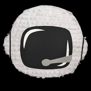 May include: A white astronaut helmet piñata with a black visor and a gray microphone. The piñata is made of white paper fringe and has black string attached for hanging.