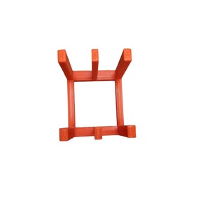 May include: A bright orange, square plant stand with a minimalist design. The stand has four vertical supports and a square base, perfect for displaying small potted plants. The stand is made of a solid material and is set against a white background.