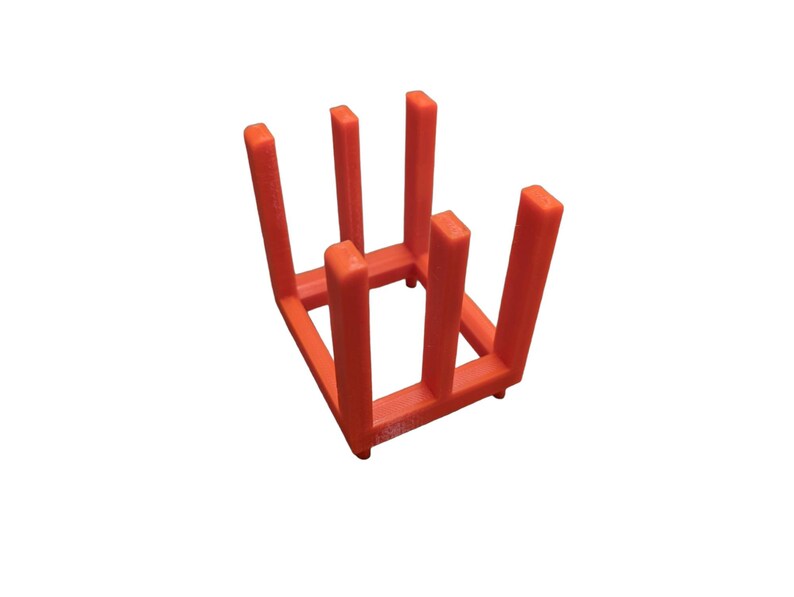 May include: An orange, 3D-printed, square-shaped rack with six vertical supports. The rack is designed to hold items and is made of a solid, vibrant orange plastic. The supports are evenly spaced and the base has small feet.