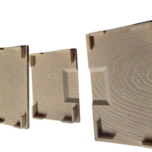 Pu&ograve; includere: Tre pannelli di legno di diverse dimensioni, ciascuno con un motivo circolare concentrico strutturato che ricorda la venatura del legno. I pannelli hanno elementi angolari e laterali rialzati, creando un effetto tridimensionale. Il legno &egrave; di colore marrone chiaro.