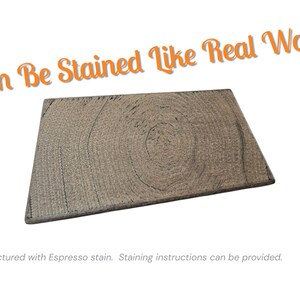 Pu&ograve; includere: Una tavola di legno rettangolare con un motivo a venature naturali, tinta con un colore espresso. Il testo "Can Be Stained Like Real Wood" &egrave; visualizzato in arancione. L'immagine mostra un primo piano della trama del legno.