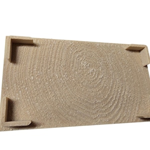 Pu&ograve; includere: Un vassoio rettangolare in legno marrone chiaro con una superficie strutturata che ricorda gli anelli degli alberi. Il vassoio ha quattro supporti angolari. Il design conferisce al vassoio un'estetica rustica e naturale.