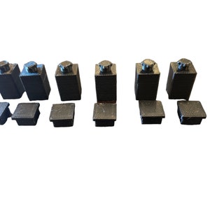 May include: A set of six black plastic furniture leg caps with a square top and a round bottom. The caps are arranged in two rows of three.