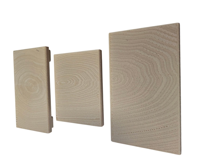 Pu&ograve; includere: Tre blocchi di legno rettangolari di diverse dimensioni, disposti uno accanto all'altro. I blocchi sono di colore chiaro, forse non rifiniti, e mostrano motivi di venature del legno visibili. La venatura del legno crea una texture naturale e organica.