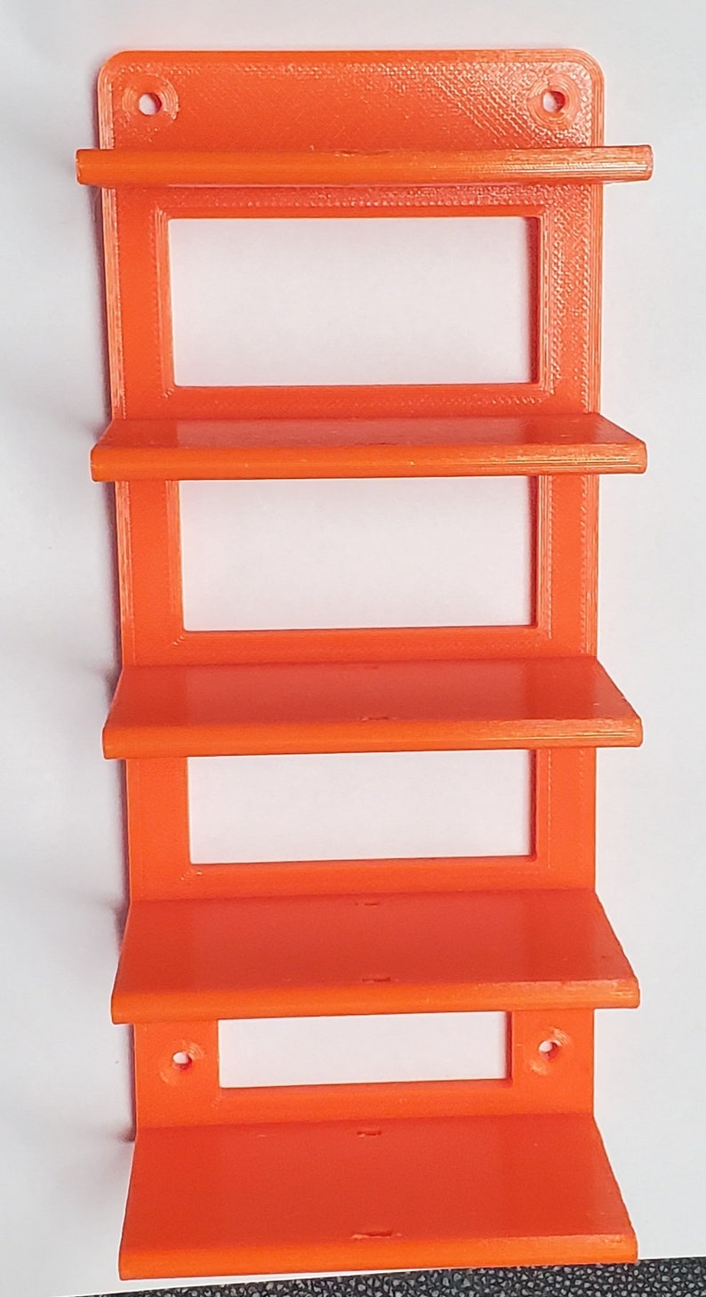 K&ouml;nnte beinhalten: Orange Wandregal mit vier Regalen und einem rechteckigen Design. Das Regal hat oben zwei L&ouml;cher zur Befestigung. Die Regale sind gleichm&auml;&szlig;ig angeordnet und haben eine schlichte, moderne &Auml;sthetik. Das Regal besteht aus einem durchg&auml;ngigen orangen Material.