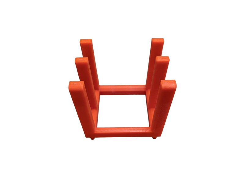 May include: An orange, 3D-printed, rectangular stand with a series of vertical supports. The stand is designed to hold items upright. The stand is made of a solid, opaque material and is set against a white background.