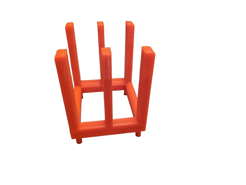 May include: An orange, open-sided, rectangular storage rack with vertical supports. The rack has a grid-like structure with four uprights and a base. The design is simple and modern, suitable for organizing items.