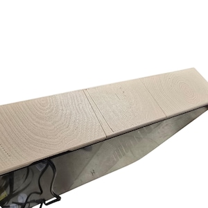 Pu&ograve; includere: Una mensola in legno chiaro con un motivo a venature naturali. La mensola ha una forma rettangolare e sembra far parte di un mobile pi&ugrave; grande. La mensola &egrave; sostenuta da una struttura in metallo nero.