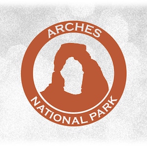 May include: A brown circle with the text "ARCHES NATIONAL PARK" in white lettering around the edge. Inside the circle is a silhouette of Delicate Arch, a natural sandstone arch in Arches National Park, Utah.