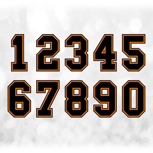 May include: A set of black numbers with orange outlines, ranging from 0 to 9, displayed against a blurred, light gray background. The numbers have a collegiate or athletic style, suitable for sports jerseys or team branding.