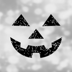 May include: Black and white silhouette of a jack-o'-lantern face with a wide smile and triangular eyes. The face is on a blurry white background.