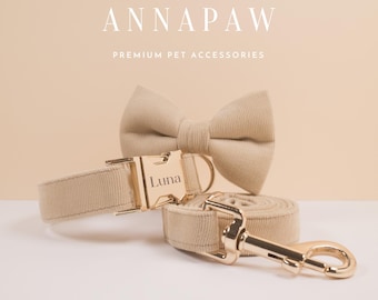 May include: A beige dog collar and lead set with a gold buckle and clasp. The collar has the name "Luna" engraved on the buckle. The set also includes a matching beige bow tie.