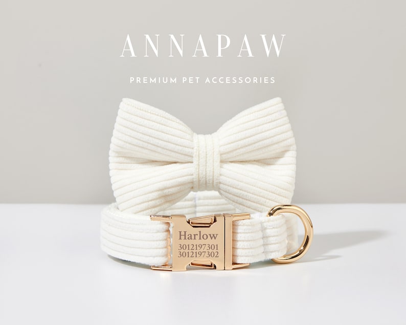 K&ouml;nnte beinhalten: Ein wei&szlig;es Hundehalsband aus Baumwolle mit einer goldenen Schnalle und einer passenden wei&szlig;en Baumwoll-Fliege. Das Halsband tr&auml;gt den Namen "Harlow" und die Nummern "3012197301 3012197302" sind in die Schnalle graviert. Der Text "ANNAPAW PREMIUM PET ACCESSORIES" wird &uuml;ber dem Halsband und der Fliege angezeigt.