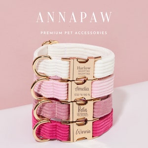 May include: Four personalized dog collars in different colors, stacked on top of each other. The collars are made of a soft, velvety material and have gold metal buckles with engraved names and phone numbers. The collars are white, pink, light pink, and hot pink.